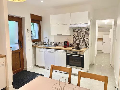 une cuisine avec des armoires blanches et une table et des chaises dans l'établissement Le Beuty, à La Bresse