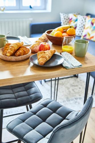 une table en bois avec des plaques de croissants et des oranges dans l'établissement BE-2G - Appartement F2 pour 1-2 pers au 2ème étage au centre de Mulhouse, à Mulhouse