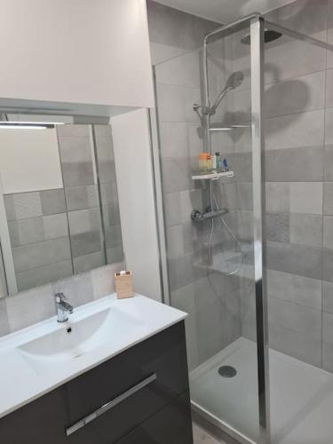 une salle de bain avec un lavabo et une douche dans l'établissement Hébergement, à Ouistreham