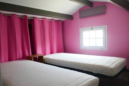2 Betten in einem Zimmer mit rosa Wänden und einem Fenster in der Unterkunft Grande Maison 200m de la plage à Bretignolles Mer plus piscines partagées in Brétignolles-sur-Mer