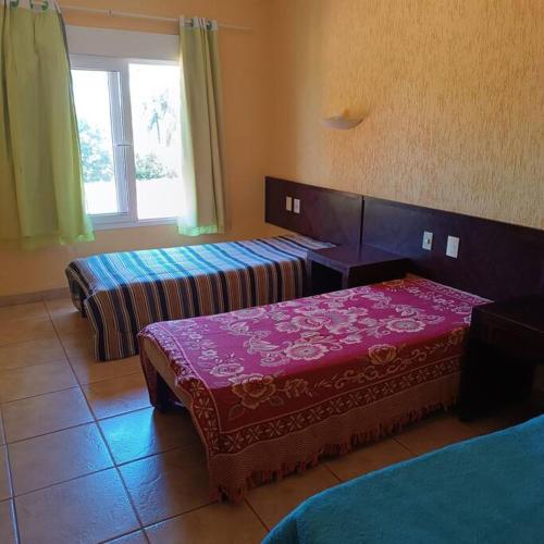 una camera d'albergo con due letti e una finestra di Chalés Confort 2 a Pimenta
