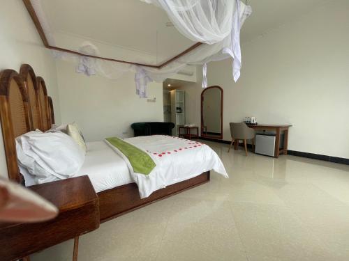 Un dormitorio con una cama, una mesa y un escritorio. en Minah Bungalows, en Nungwi
