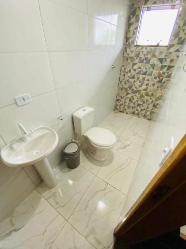 a white bathroom with a toilet and a sink at Dk residêncial CASA INTEIRA in Pontal do Paraná