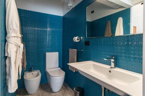 a blue bathroom with a sink and a toilet at Mina Suites in Cervia