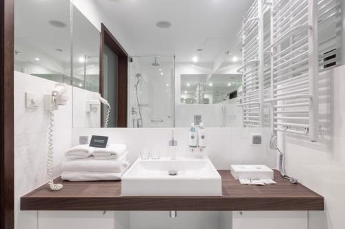 a white bathroom with a sink and a mirror at Marine Hotel by Zdrojowa in Kołobrzeg