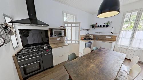 Il comprend une cuisine équipée d'une cuisinière et d'une table à manger. dans l'établissement Villa de Prestige à 400m de la plage Prestige CAMIMAX à 400m de la plage, à La Faute-sur-Mer