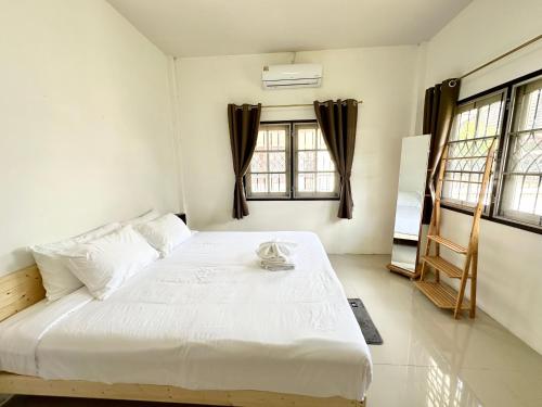 a white bed in a room with windows at Cozy 3 BR house & green lawn near Airport & Old town in Chiang Mai
