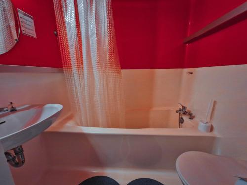 une salle de bain avec une baignoire et un lavabo et des murs rouges dans l'établissement Studio 5 pers skis aux pieds, proche commerces, animaux admis à Arc 1800 - FR-1-411-199, à Arc 1800