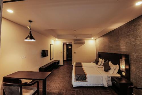 a hotel room with a bed and a table and a desk at Avoki Resorts in Trivandrum