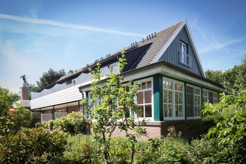 a house with a conservatory in a garden at Gästehaus Orion - Einzelzimmer 11 in Spiekeroog