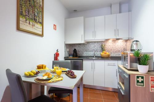 a kitchen with white cabinets and a table with fruit on it at Host Wise - Stylish Adorable Flat in Gaia in Vila Nova de Gaia