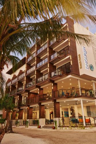 a hotel with a palm tree in front of it at Beach Hotel Dhigurah in Dhigurah
