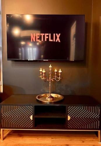 - une table avec une télévision sur un mur orné d'une mosaïque dans l'établissement Love room, à Esbly