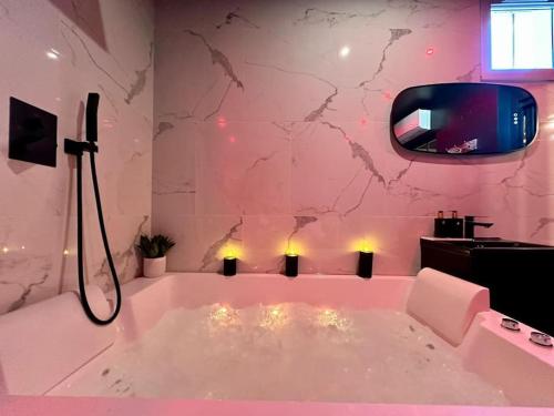 La salle de bains est pourvue d'une baignoire et d'une télévision murale. dans l'établissement Love room, à Esbly