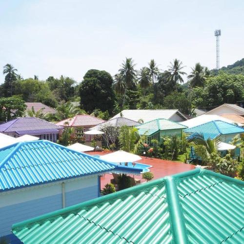 a group of houses with blue roofs and palm trees at Phetmanee Resort in Ko Yao Noi