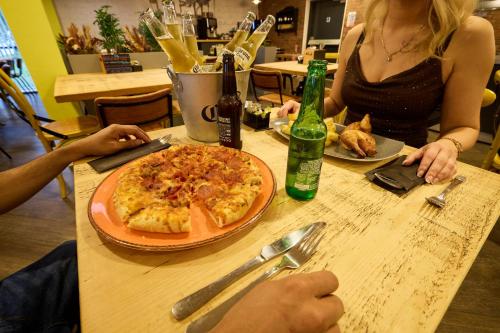 a woman sitting at a table with a pizza at Holiday Inn - the niu, Loom Manchester North by IHG in Manchester