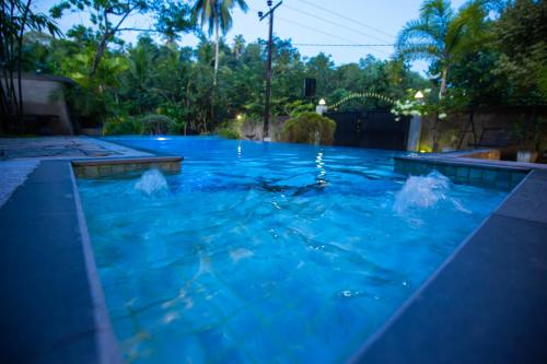 a swimming pool with blue water at night at Saku Residence in Unawatuna