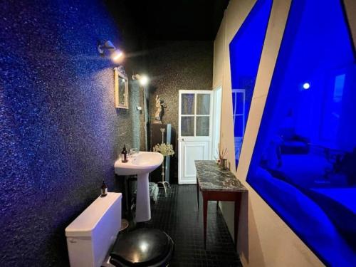 La salle de bains est pourvue d'un lavabo blanc et d'un mur bleu. dans l'établissement La Galerie des Archives-Unique and élégant Gem-MARAIS AirCond, à Paris