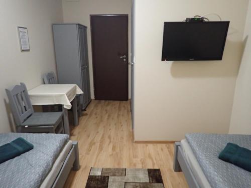 a room with two beds and a table and a television at Noclegi Kochlice in Kochlice