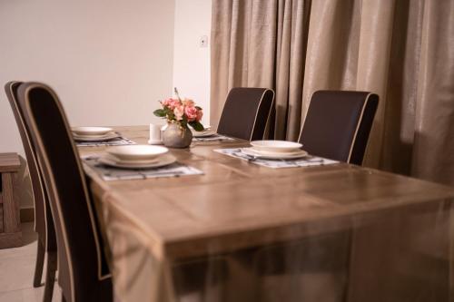 a table with chairs and plates and a vase with flowers at NSK Apparts in Nouakchott