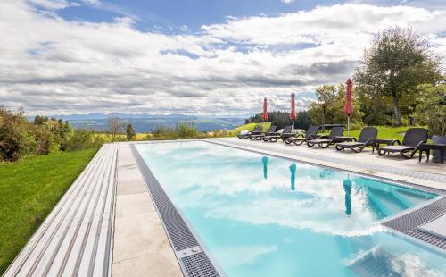 a swimming pool with chaise lounge chairs around it at Bergwald Panorama Suiten in Scheidegg