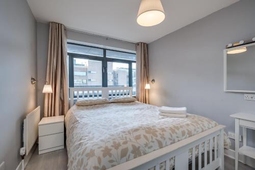 Un dormitorio con una cama y una ventana grande en Belfast City apartment with free parking!, en Belfast
