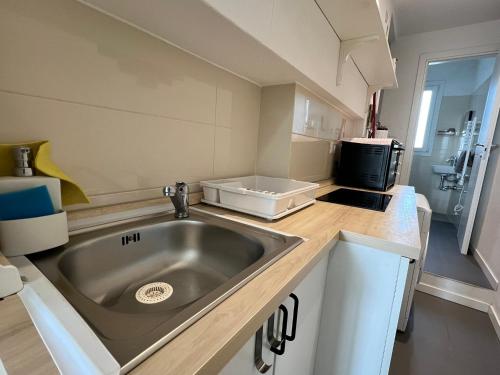 a kitchen with a stainless steel sink and a microwave at Alexas's Home - Wi-Fi, Netflix in Milan