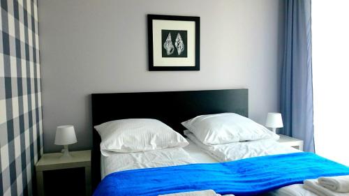 a bedroom with a bed with blue sheets and white pillows at Willa Długa No. 4 Bed & Breakfast in Gdynia