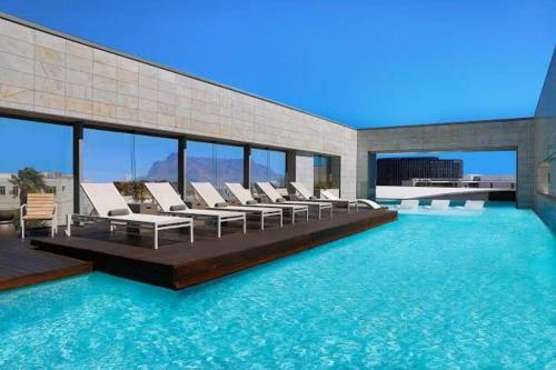 a swimming pool with lounge chairs in a building at Luxury Two Bed - Crystal Towers - Spectacular Views in Cape Town