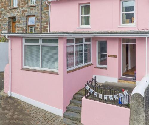 a pink house with a fence in front of it at Ellesmere New Quay in New Quay
