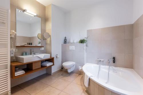 a bathroom with a tub and a toilet and a sink at Apartments am Schloss Mühldorf in Feldkirchen an der Donau