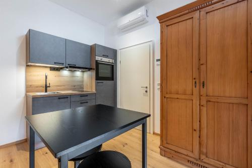 a kitchen with a black table and wooden cabinets at Apartments am Schloss Mühldorf in Feldkirchen an der Donau