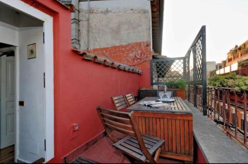 einen Balkon mit einem Tisch und Stühlen an einer roten Wand in der Unterkunft Casa Rossetti - 2 Private Terraces - 4th floor with no lift in Rom