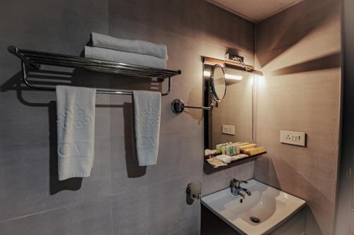 a bathroom with a sink and a mirror and towels at Avoki Resorts in Trivandrum