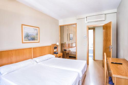 a bedroom with a white bed and a desk at Hotel Alda Castelao in Vilagarcia de Arousa