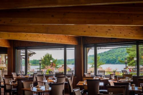 a dining room with tables and chairs and large windows at Le Manoir du Lac Delage in Stoneham