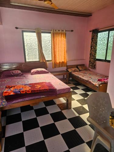 a bedroom with two beds and a checkered floor at Advait Holiday Home in Nagaon