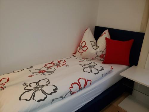 a bed with a white comforter with flowers on it at Urlaub am Krausberghof, Apartment mit Balkon und Parkplatz, Aufenthaltsraum, Sauna und Infrarotkabine, inmitten der Natur, kostenfreie Kaffeekapseln, 6 Fahrminuten zur Alpentherme Gastein und zur Schlossalmbahn, Spielplatz, großer Gartenbereich in Bad Hofgastein