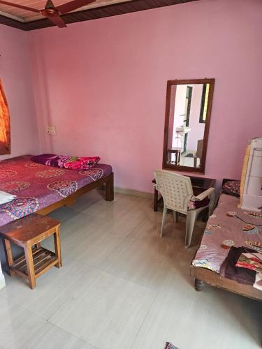 a room with two beds and a mirror and a chair at Advait Holiday Home in Nagaon