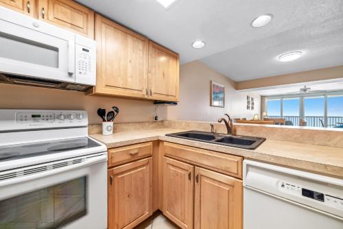 a kitchen with wooden cabinets and white appliances at Romar Tower Unit 8C in Orange Beach