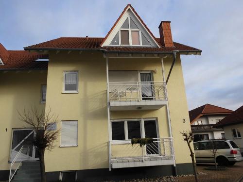 a yellow house with a balcony and a car at Ferienwohnung Spatzennest in Kronau