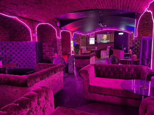 a bar with pink lighting in a room with couches at King Street Hotel in Blackburn