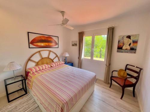 een slaapkamer met een bed, een stoel en een raam bij Suite with views of son bou beach in Son Bou