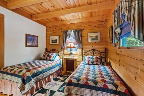 two beds in a room with wooden walls at Lakefront Log Cabin on 2 acres in Washington