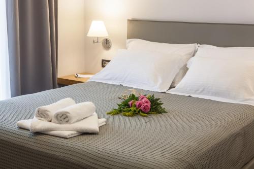 a hotel room with towels and flowers on a bed at Anemos Rooms & Apartments in Nafplio