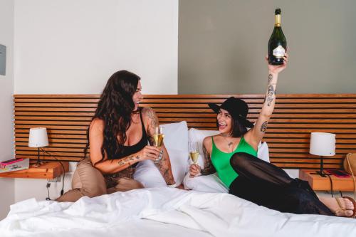 two women sitting on a bed holding glasses of wine at Romeo Hotel LGBTQ in San Juan