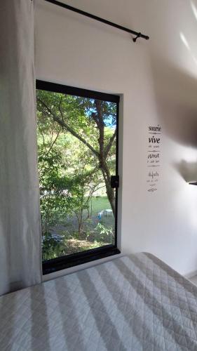 a bedroom with a window with a view of a tree at Pousada e Cervejaria Amor in Malte in Lavrinhas