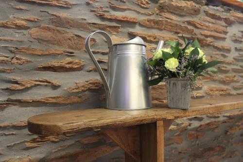 a watering can on a wooden table with a vase of flowers at Gîte L'Olivier à Filly - Nadrin, entre Houffalize et La Roche-en-Ardenne in Houffalize