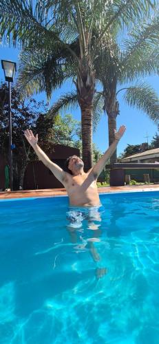 a man in a swimming pool with his arms in the air at Cabañas Apart del Sauce II in Paraná
