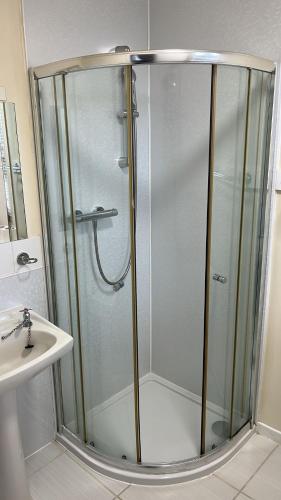 a shower with a glass door next to a sink at Novar Arms Hotel in Evanton